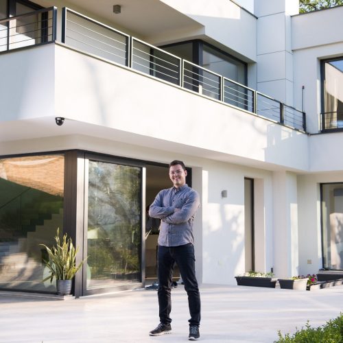 portrait of a young handsome successful man in front of his luxury home villa